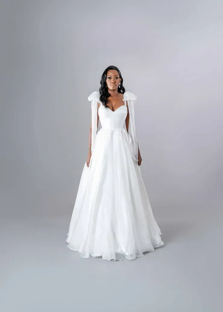 A woman is wearing a white wedding dress and gloves.