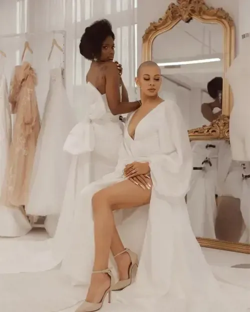 A woman in a white dress is sitting in front of a mirror.