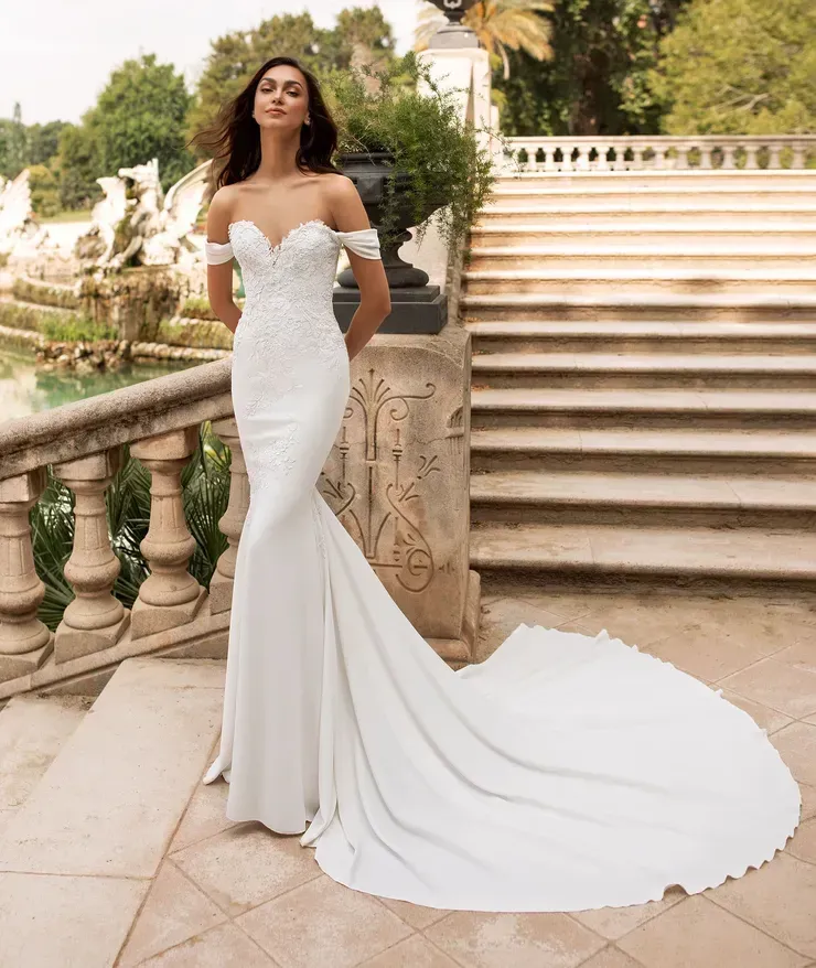 A woman in a white wedding dress is standing in front of stairs.