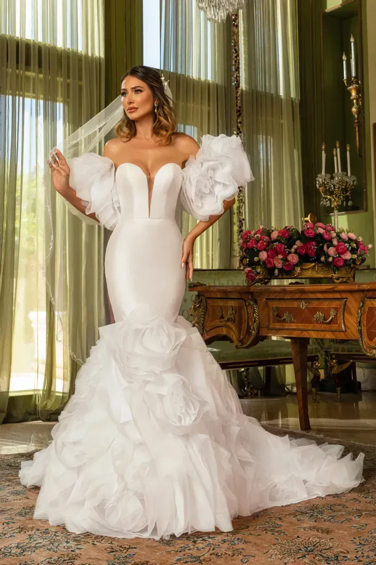 A woman in a white wedding dress and veil is standing in a room.