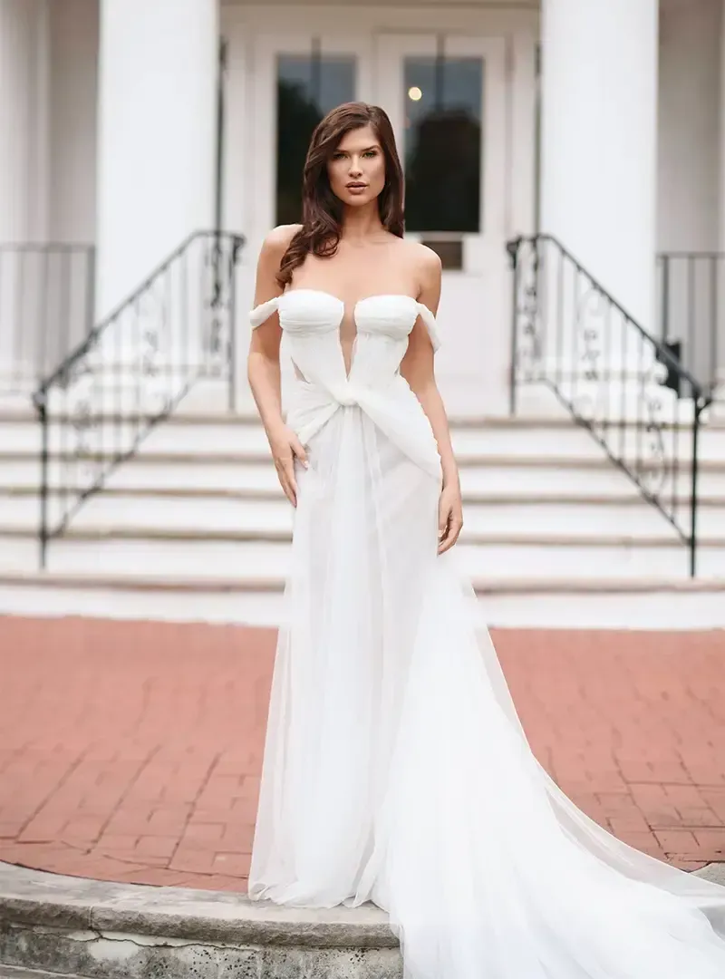 A woman in a white wedding dress is standing in front of a building.