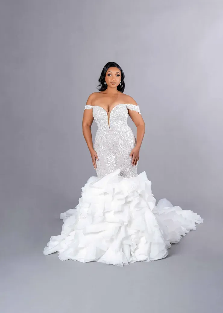 A woman in a white wedding dress is standing on a gray background.