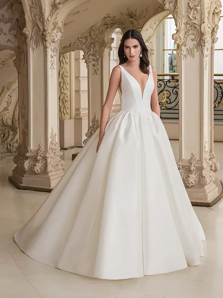 A woman in a white wedding dress is standing in front of columns.