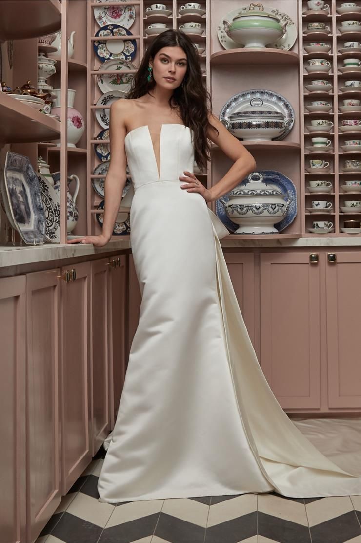 A woman in a white wedding dress is standing in a kitchen.