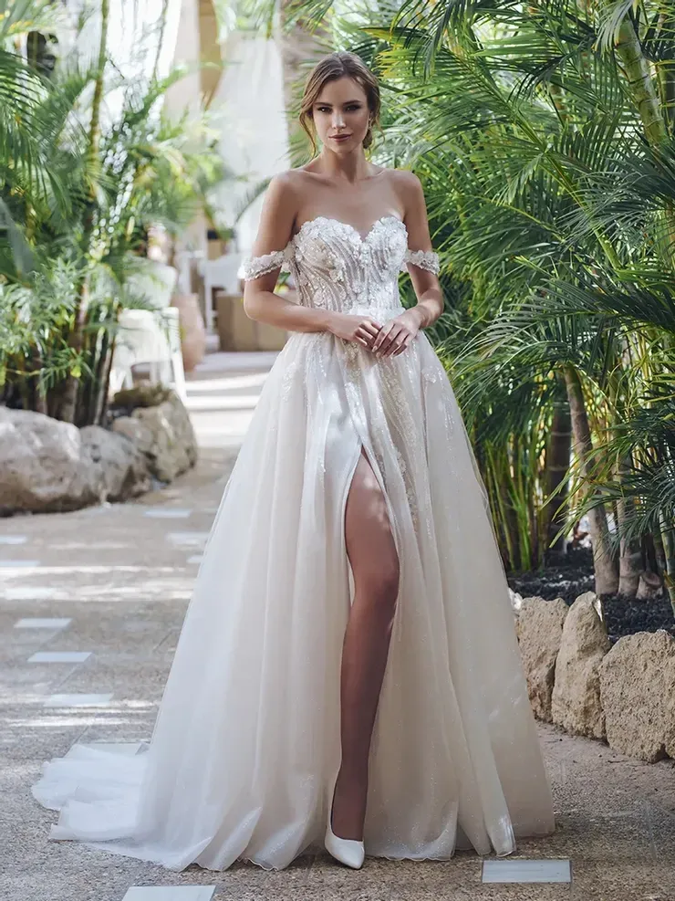A woman is wearing a white wedding dress with a high slit.