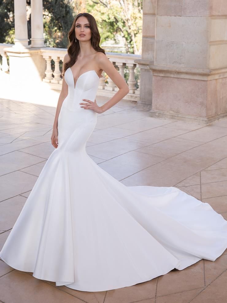 A woman in a white wedding dress is standing in front of a building.