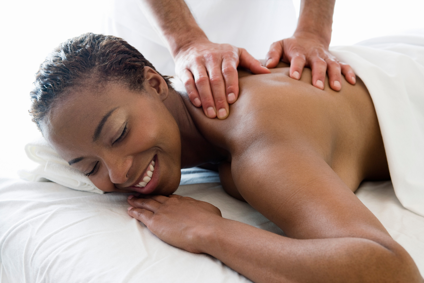 A woman is smiling while getting a massage on her back