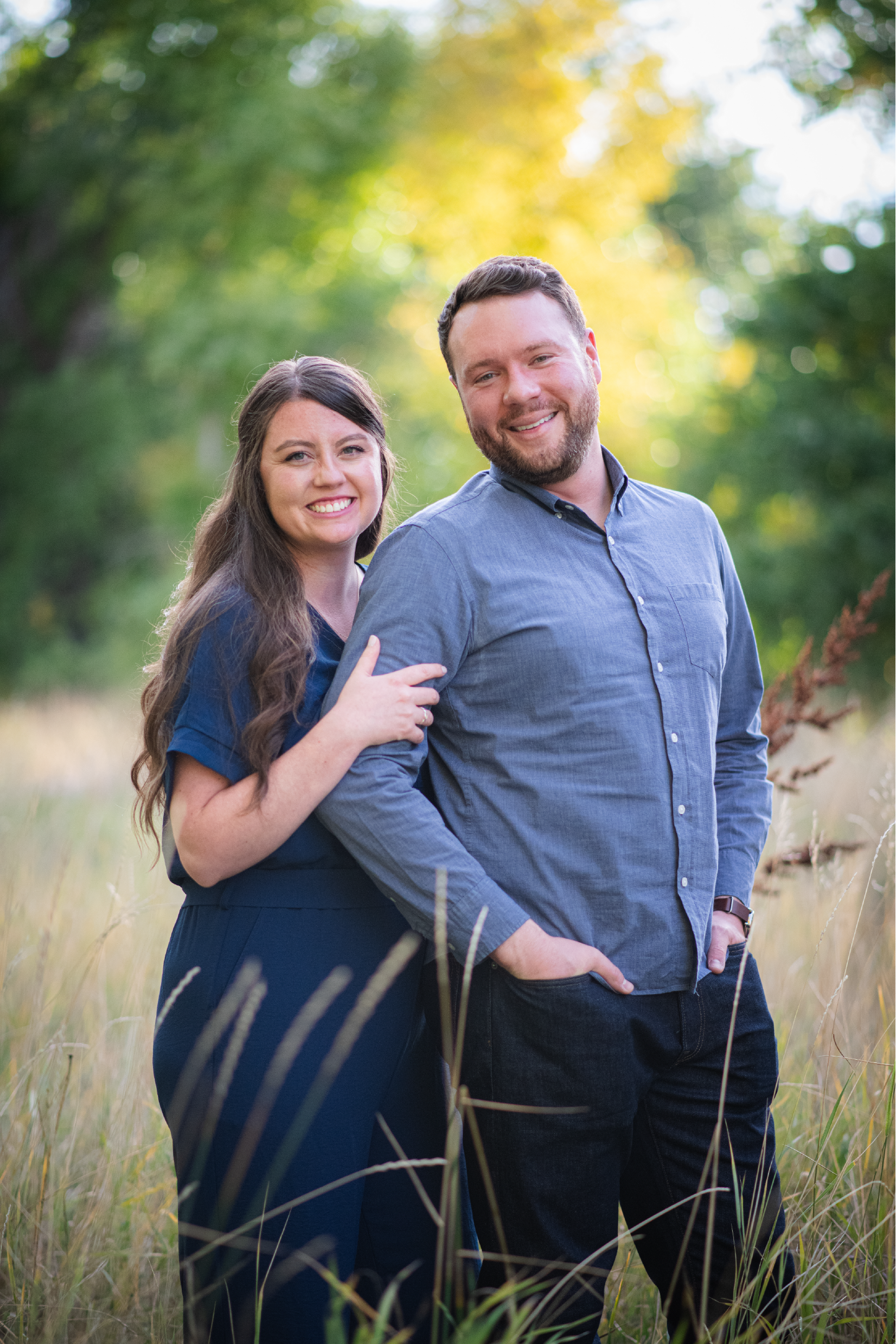 A man and a woman are posing for a picture in a field.