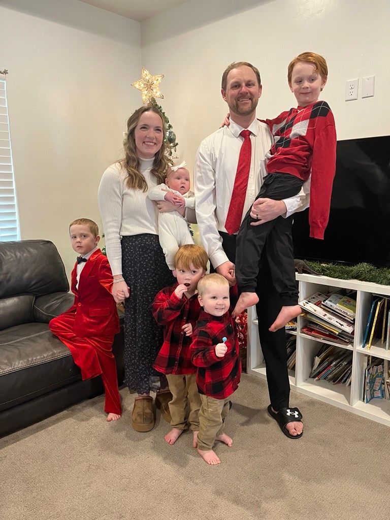 A family is posing for a picture in the woods.