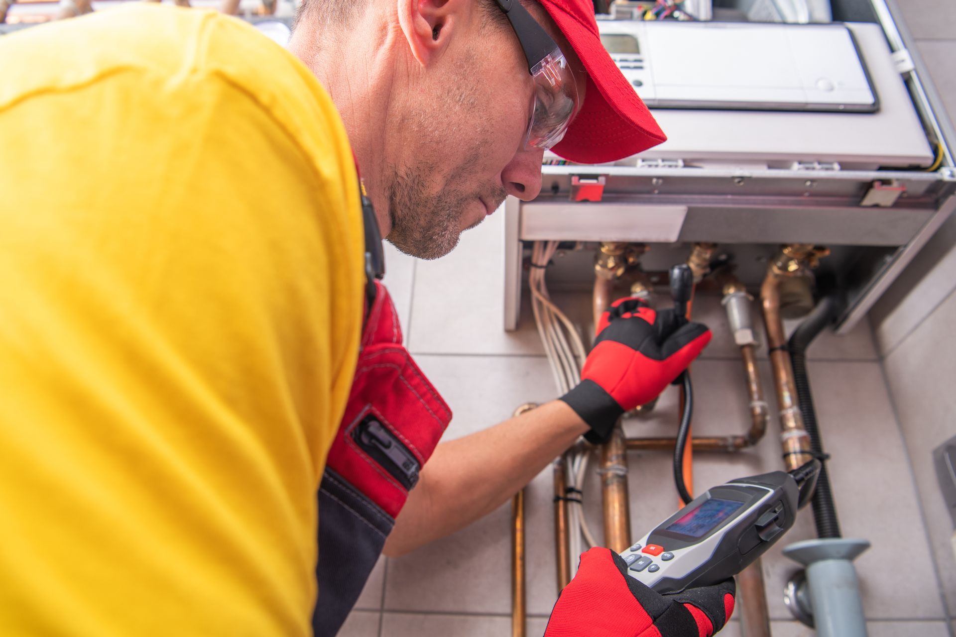 Technician using diagnostic tools while servicing heating system pipes.