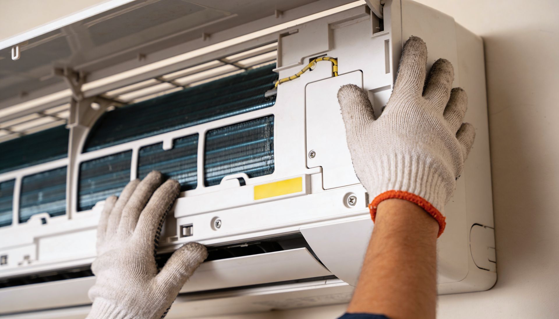 Professional air conditioning contractor performing expert maintenance on a wall-mounted unit.