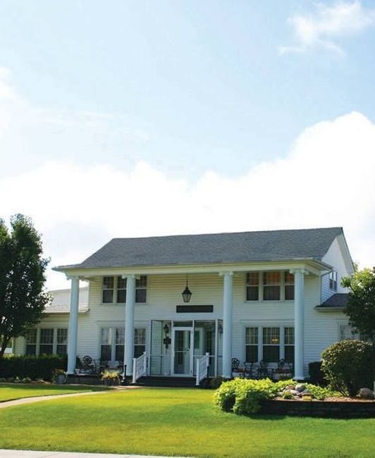 a wooden walkway leading to a gazebo overlooking a body of water at sunset .