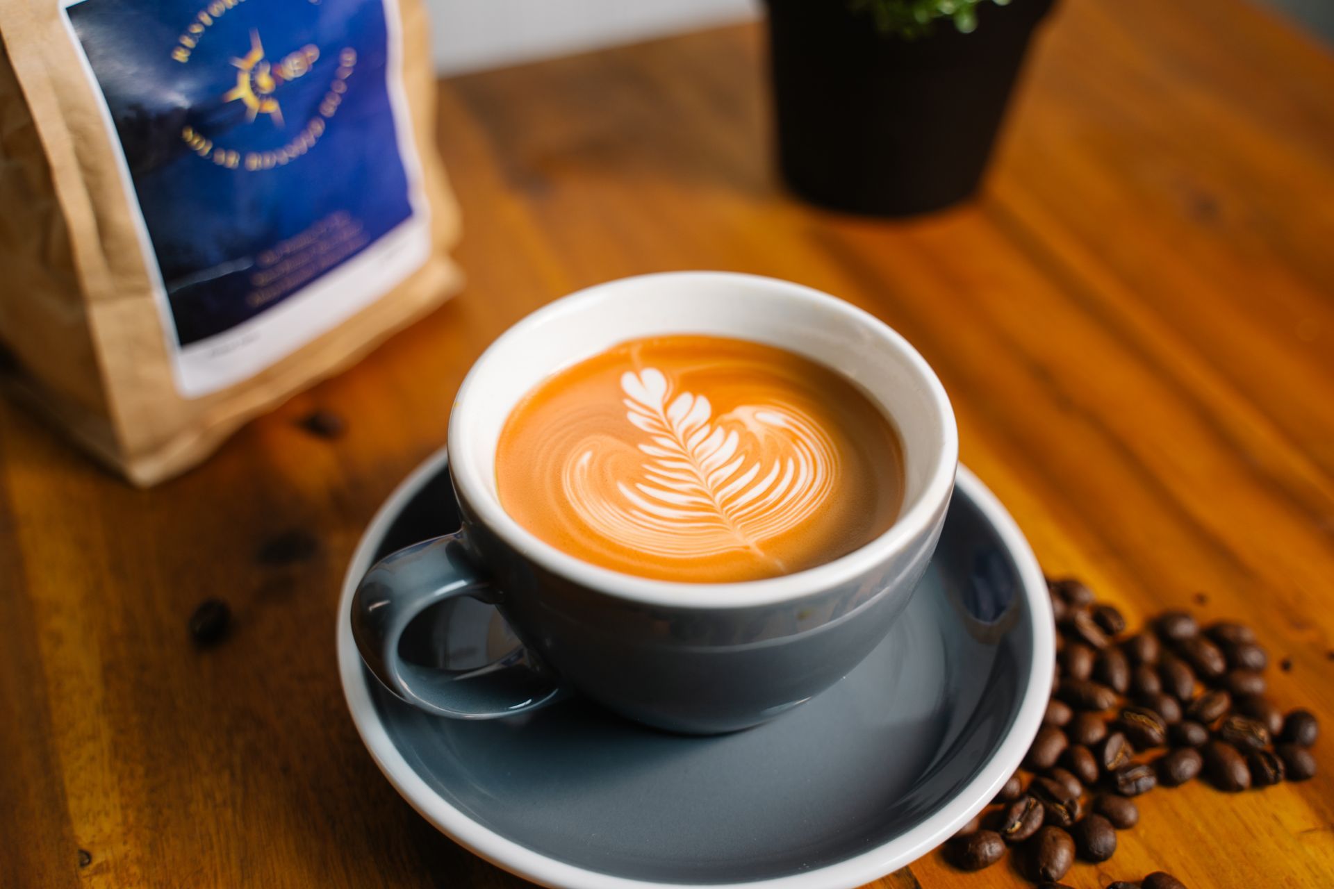 A cup of coffee on a saucer next to a bag of coffee