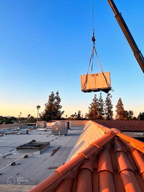 A crane is lifting a box on top of a roof
