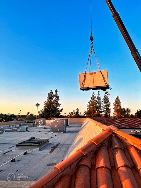 A crane is lifting a box from the roof of a building