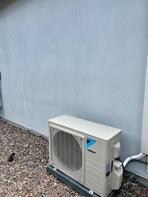 A white air conditioner is sitting outside of a building.