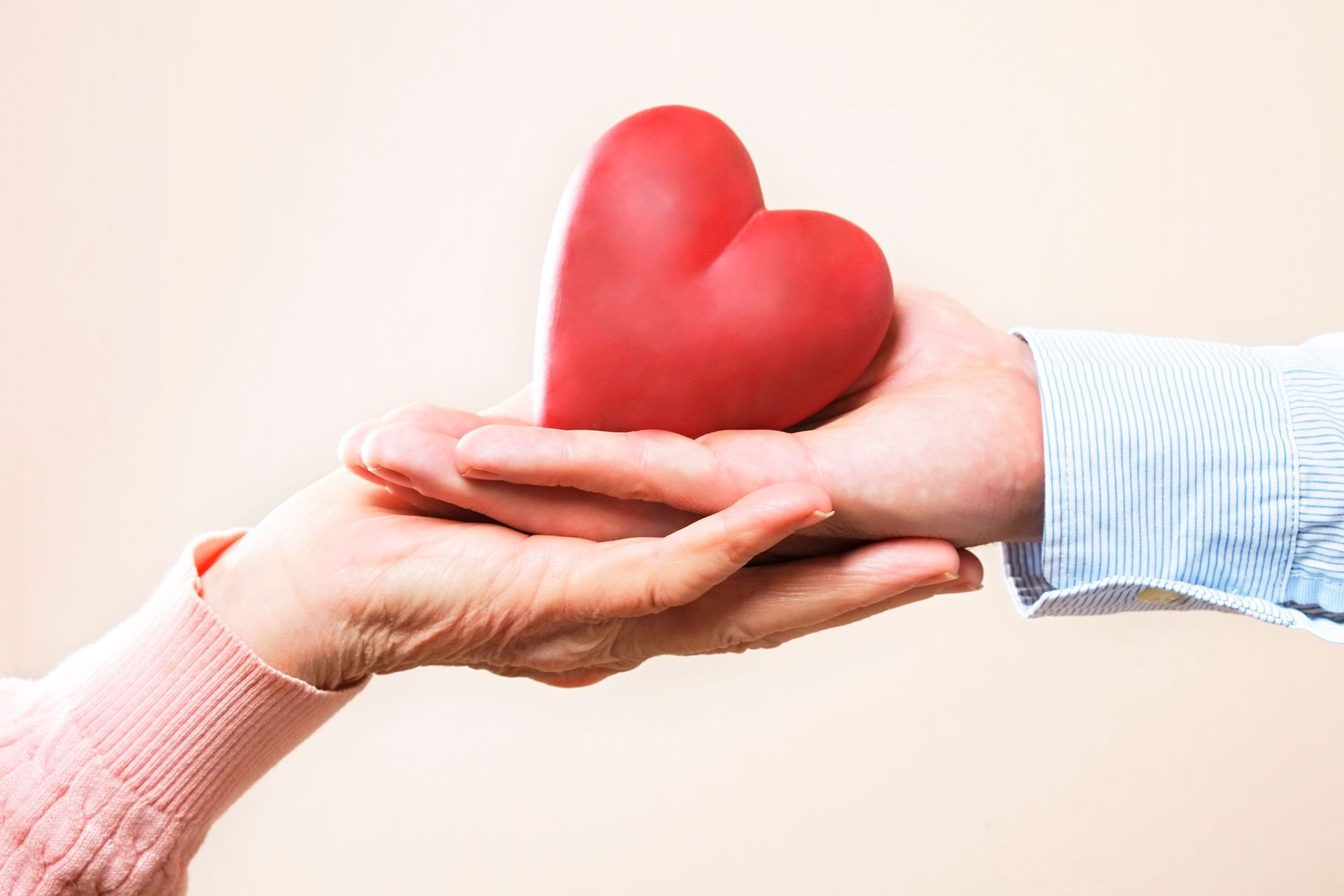 two hands holding a heart figurine