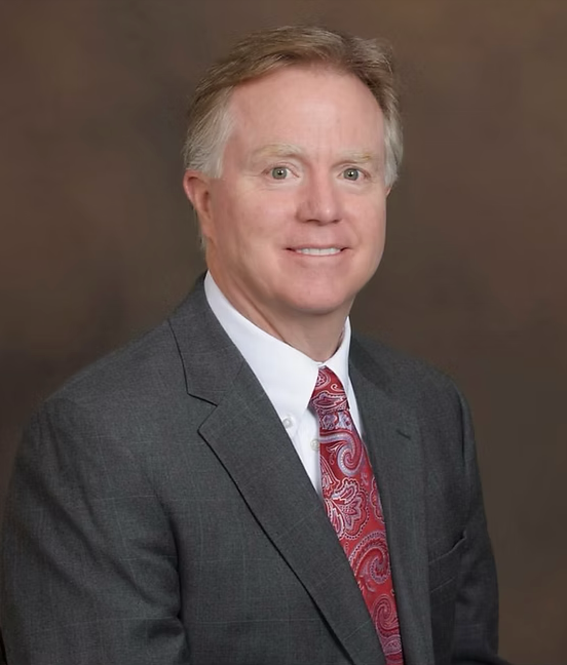 A man in a suit and tie is smiling for the camera