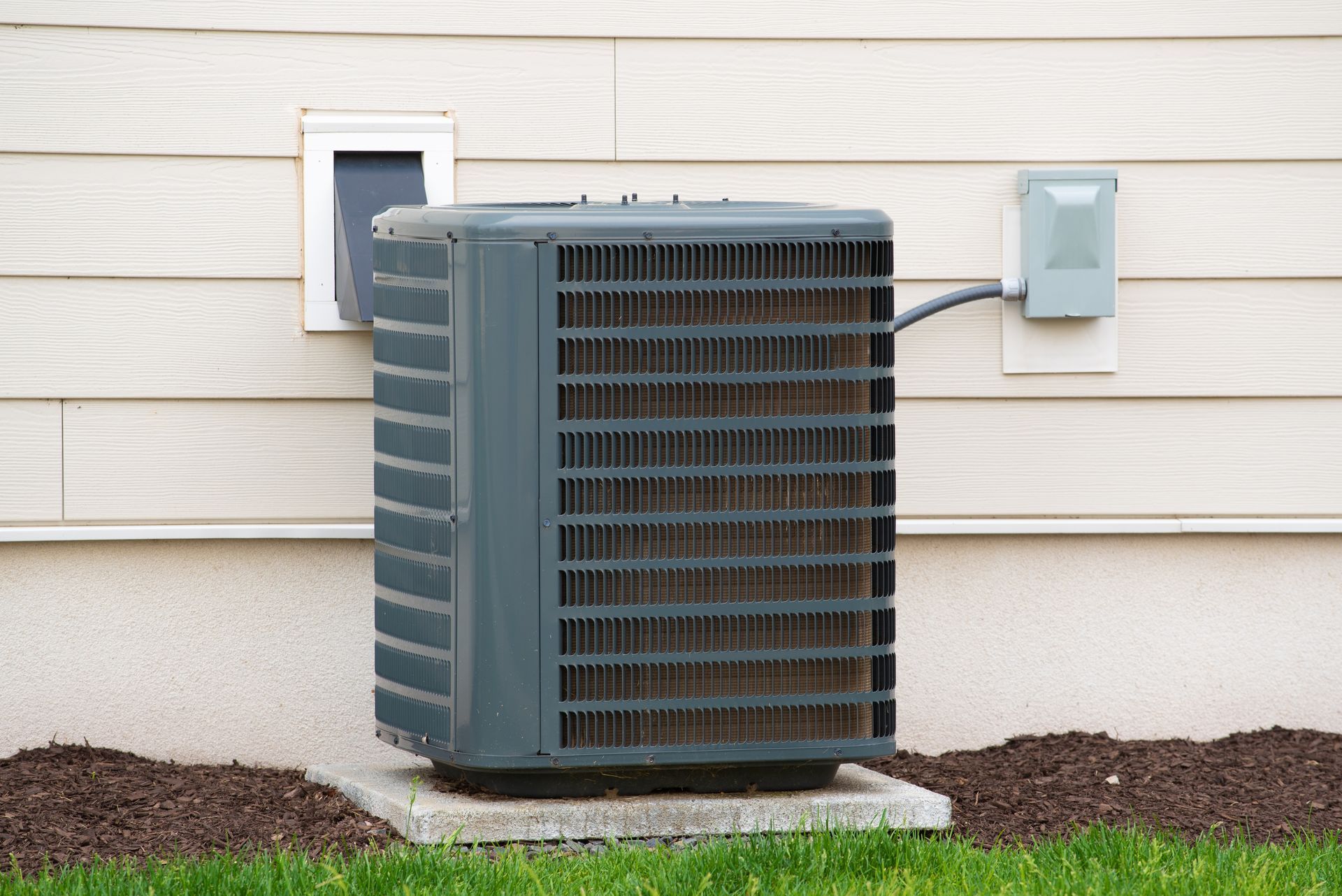 An air conditioner is sitting on the side of a house.