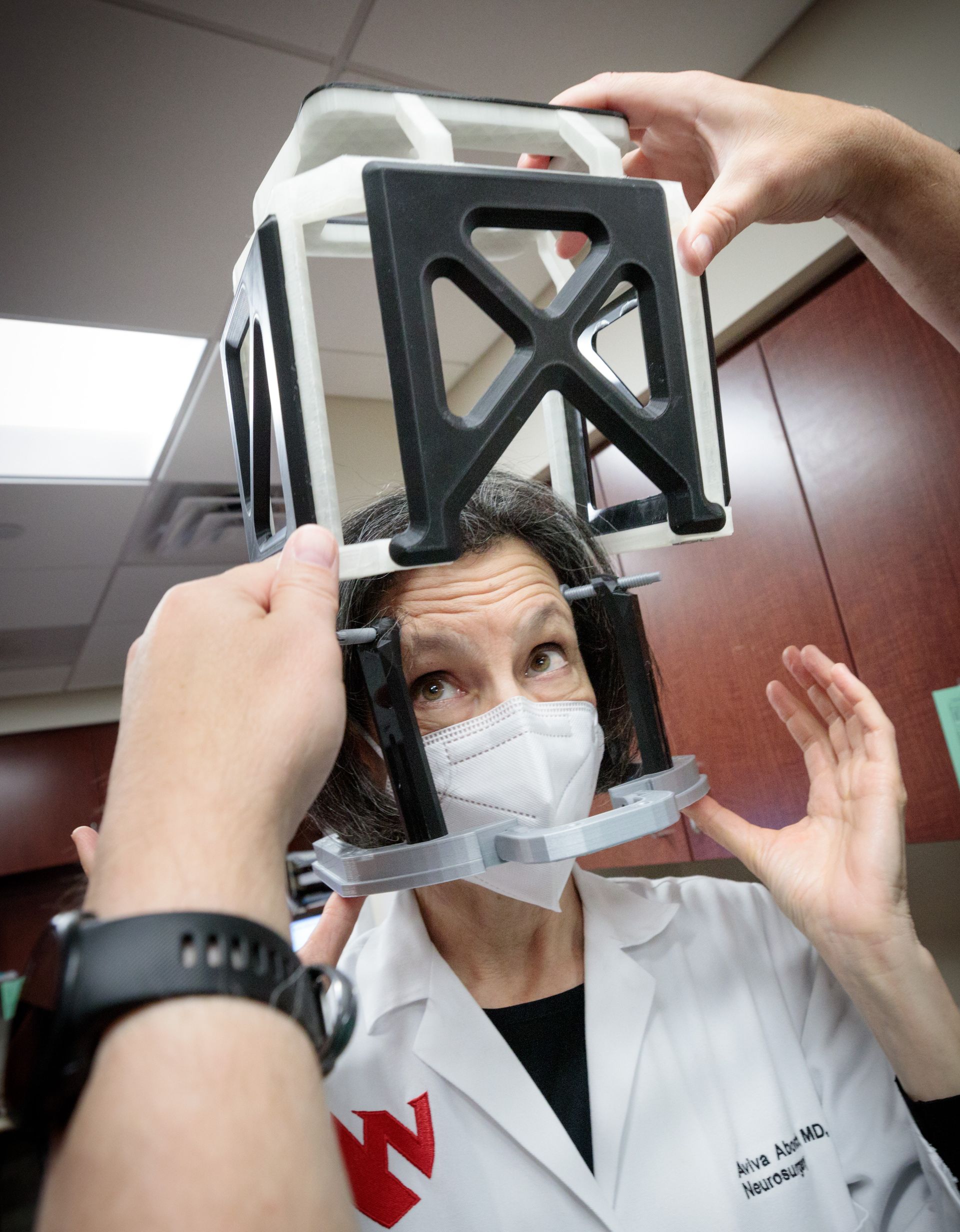 Four women in colorful outfits stand in front of a wall of red and tan industrial art.