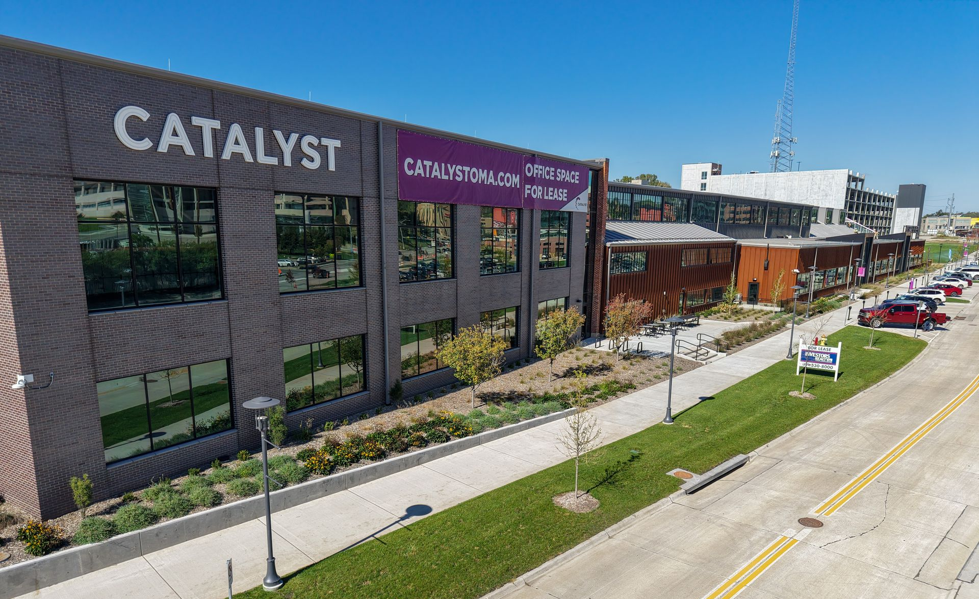 Rendering of a modern building complex with multiple sections, featuring orange and gray facades, and parking.