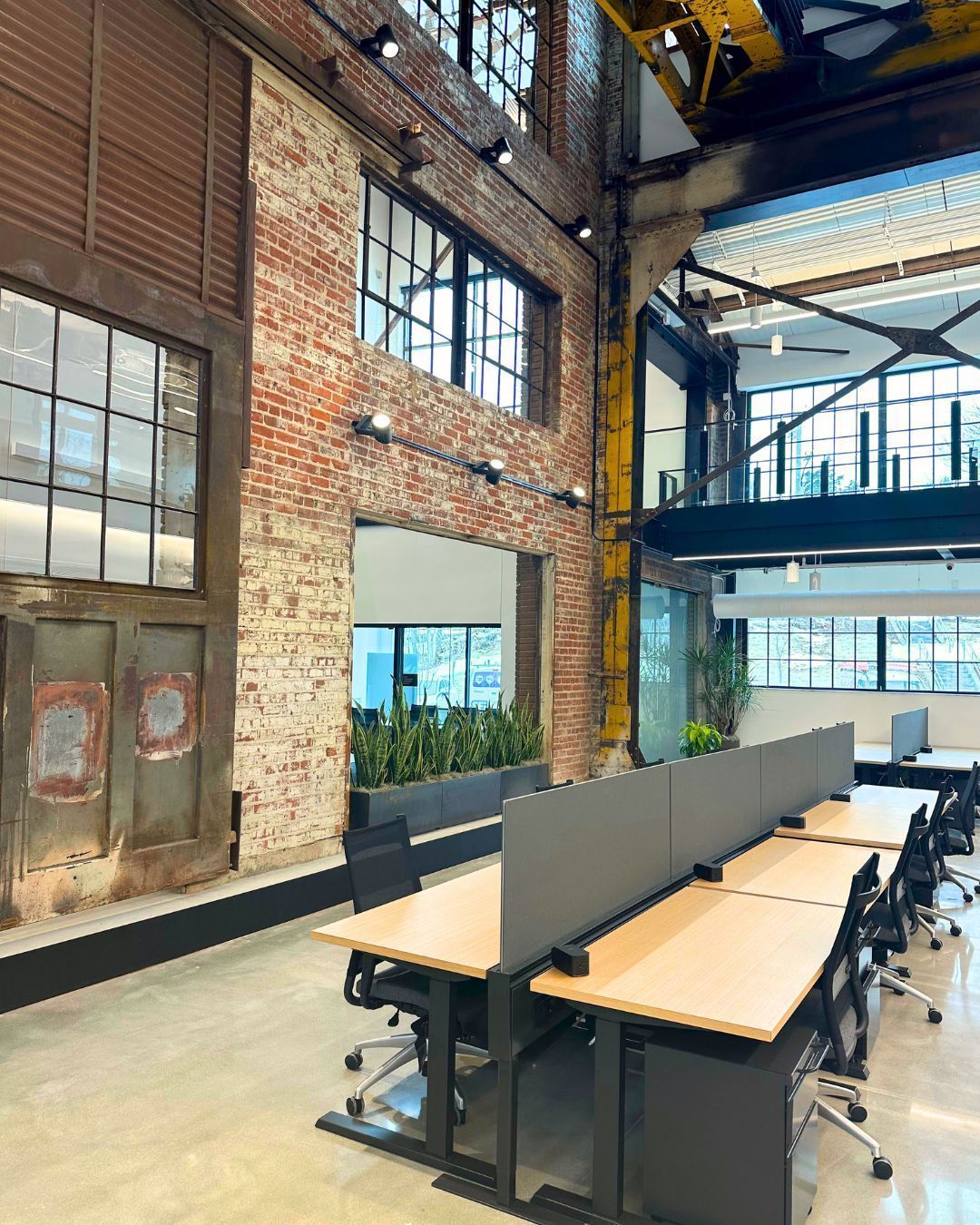 Three men in vests stand on a building under construction; blue sky, metal beams, red safety fence.
