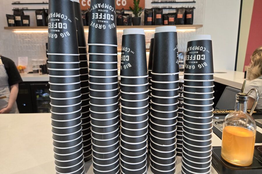 Stacks of black coffee cups with white stripes, ready for service at a cafe.