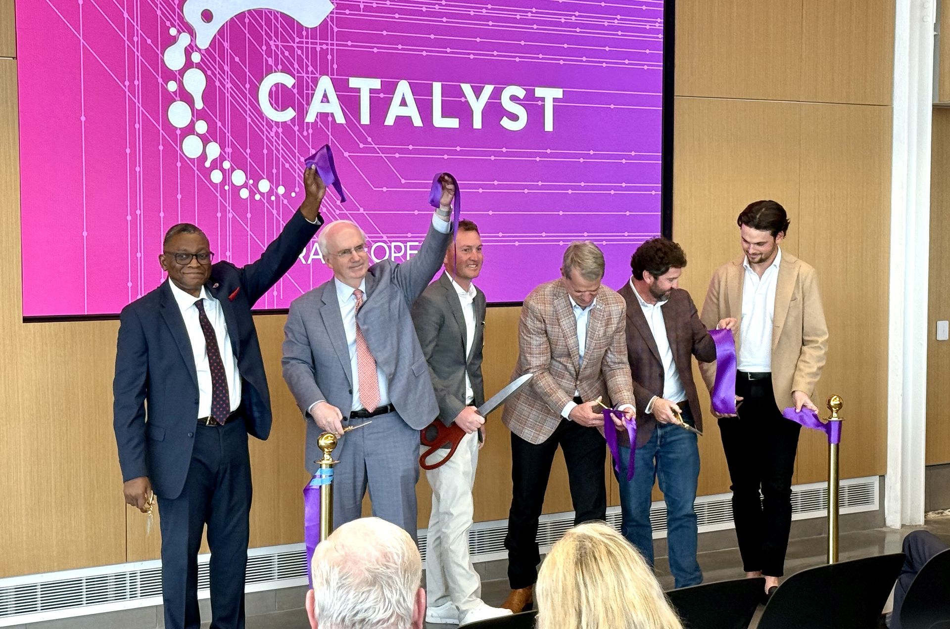 People cutting a ribbon at a Catalyst event. The sign says