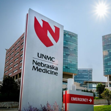 Sign for UNMC Nebraska Medicine with buildings in background; sunny day.