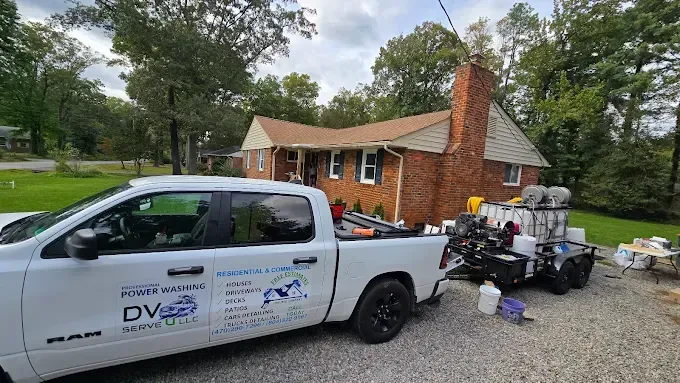 Woman in straw hat smiles, holding wine glass near a lake.