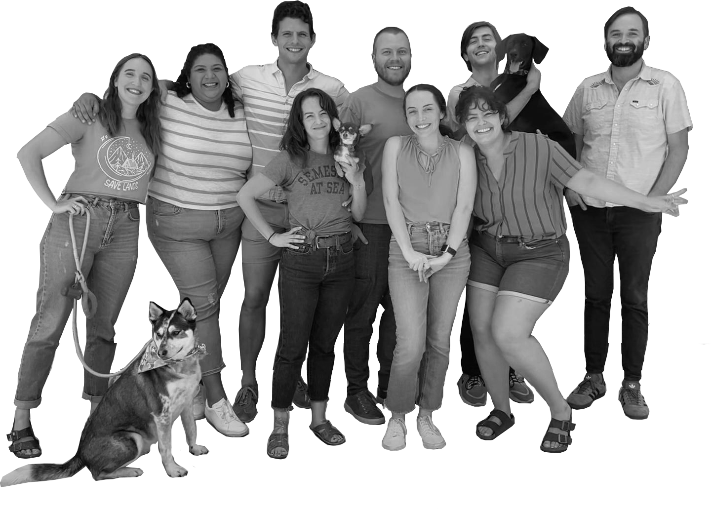 Group of people smiling, posing together, and one dog in a casual outdoor setting.