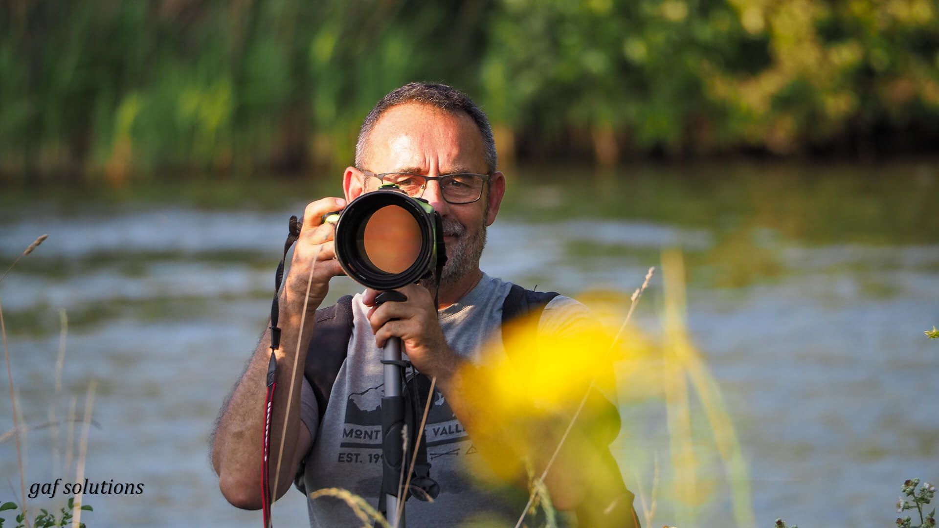 Un homme prend une photo d'une rivière avec un appareil photo.
