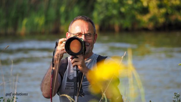 Un homme prend une photo d'une rivière avec un appareil photo.