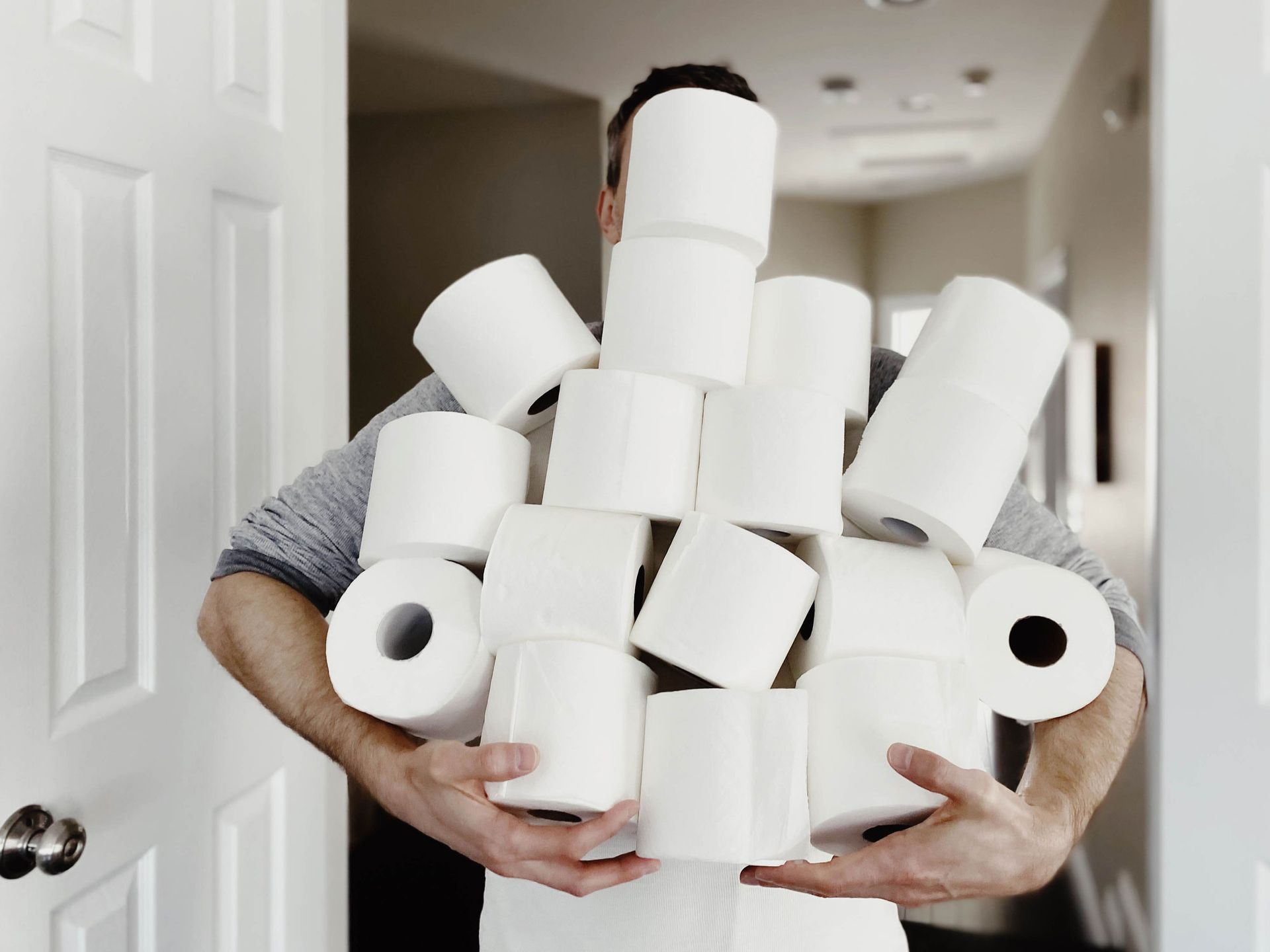 A man is holding rolls of toilet paper in front of his face
