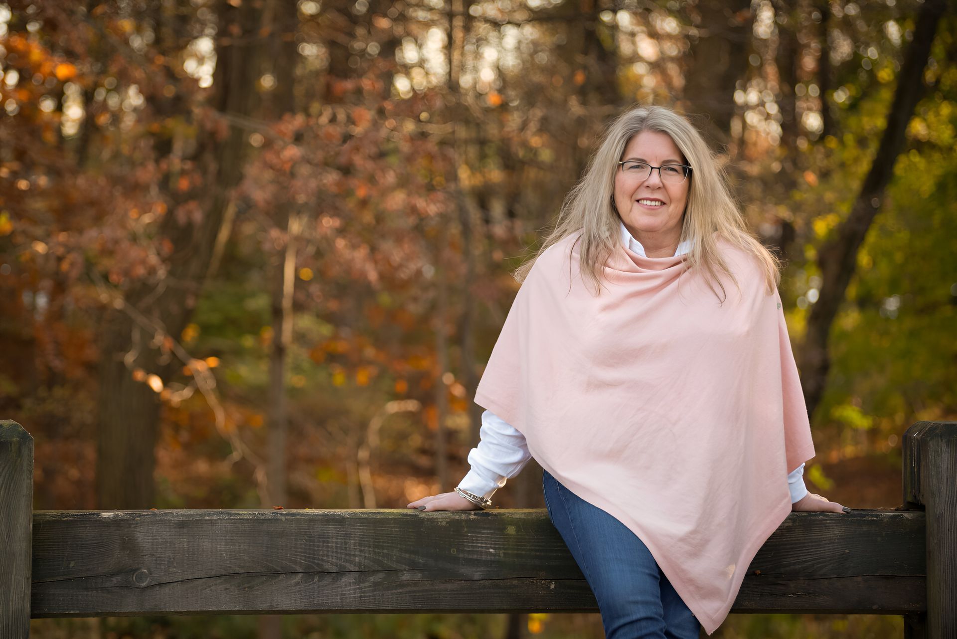 A woman is leaning on a wooden bench in a garden.