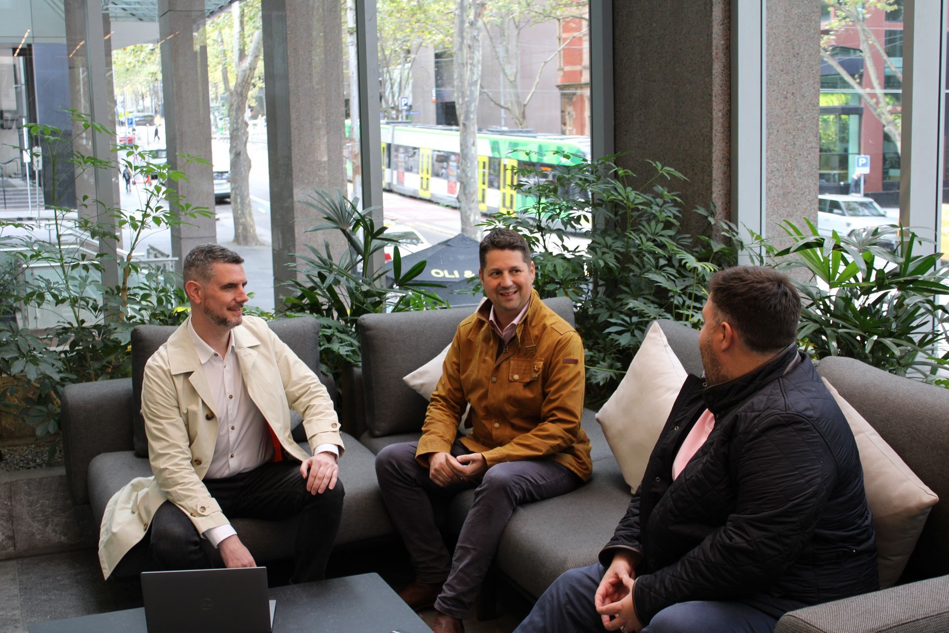 Three men are sitting on a couch talking to each other.