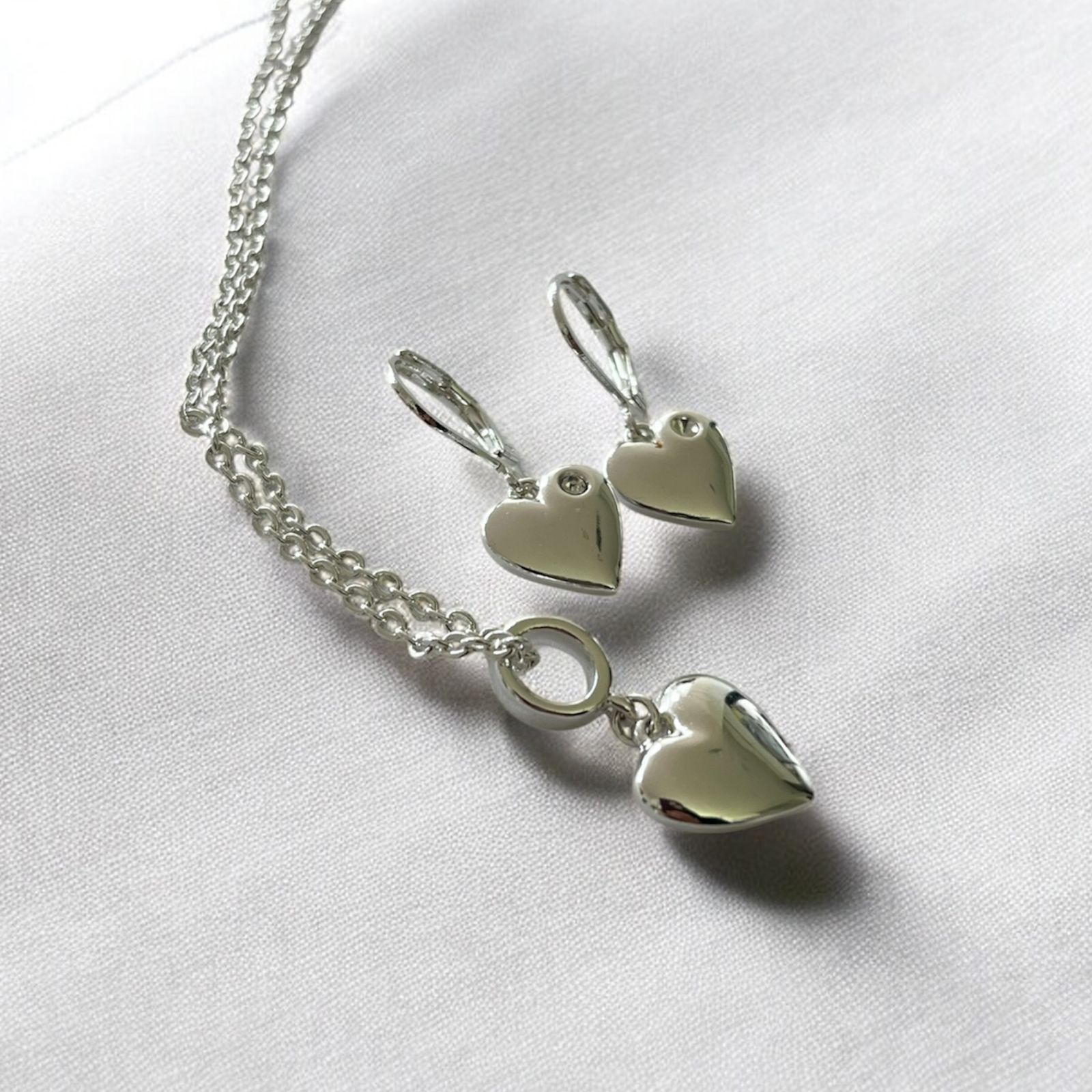 Juego de pendientes: varios pendientes con corazones y coronas, sobre cartulina rosa y blanca.