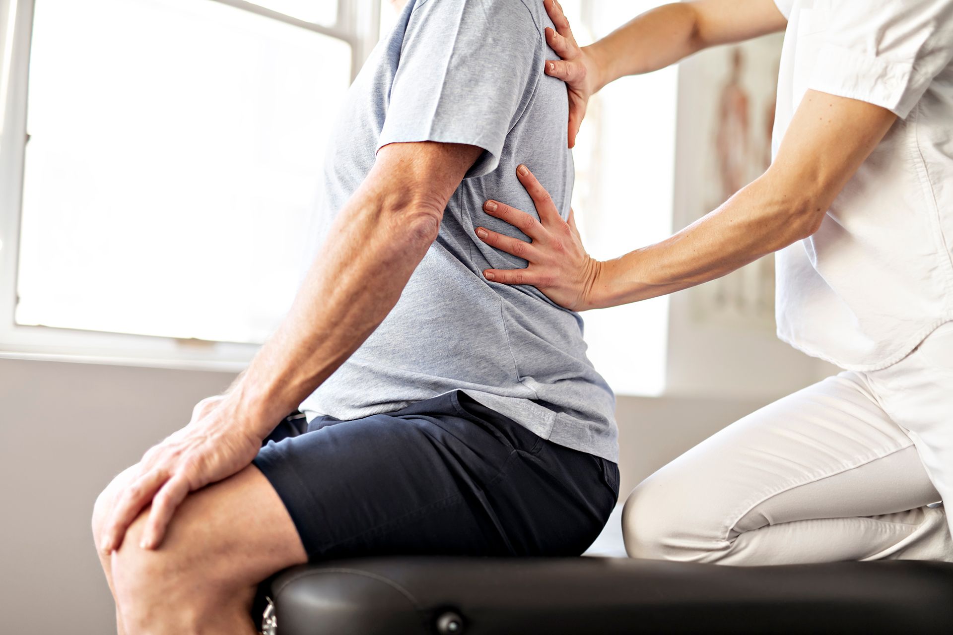 A man is sitting on a table getting a massage from a nurse.