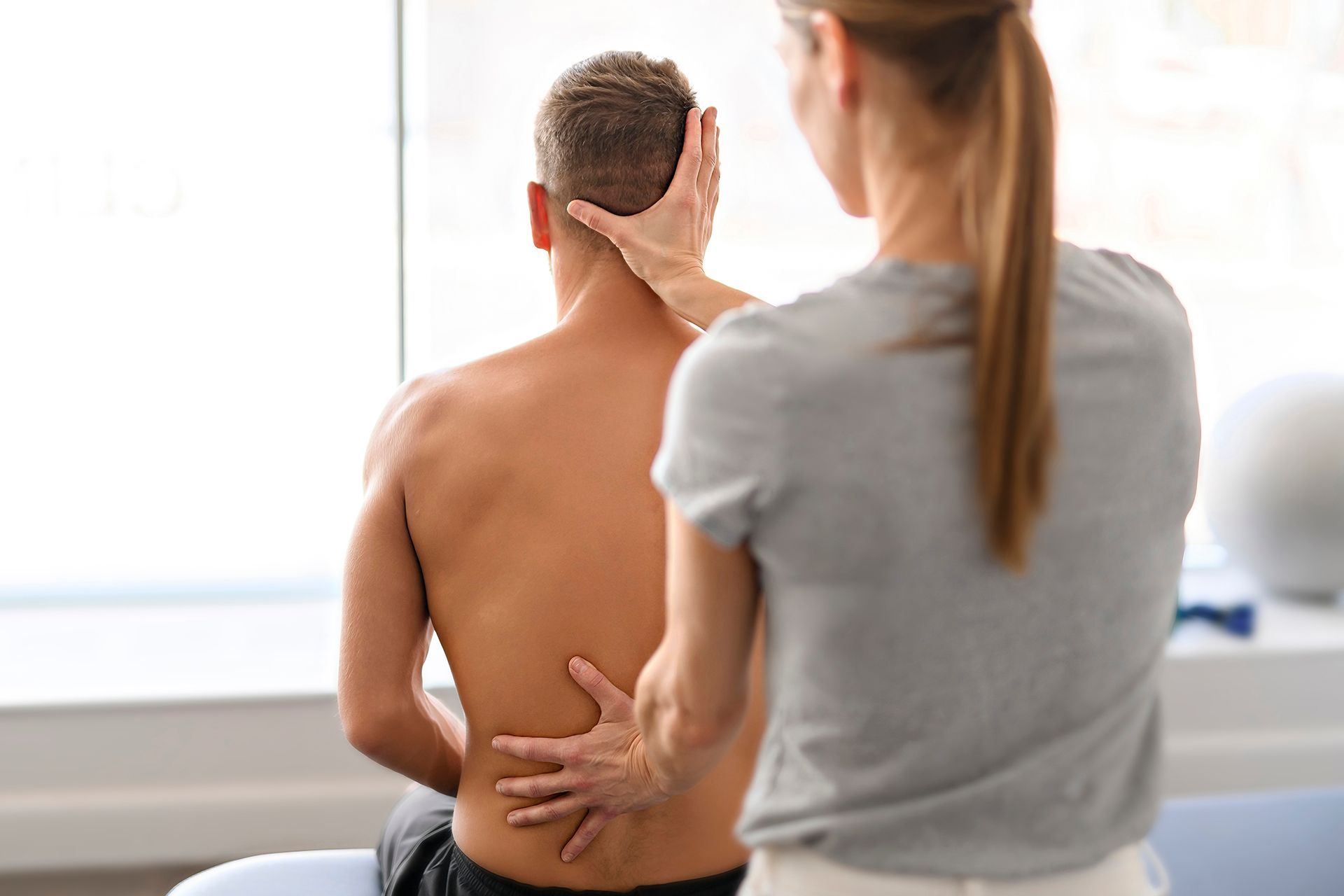 A woman is giving a man a massage in a hospital.