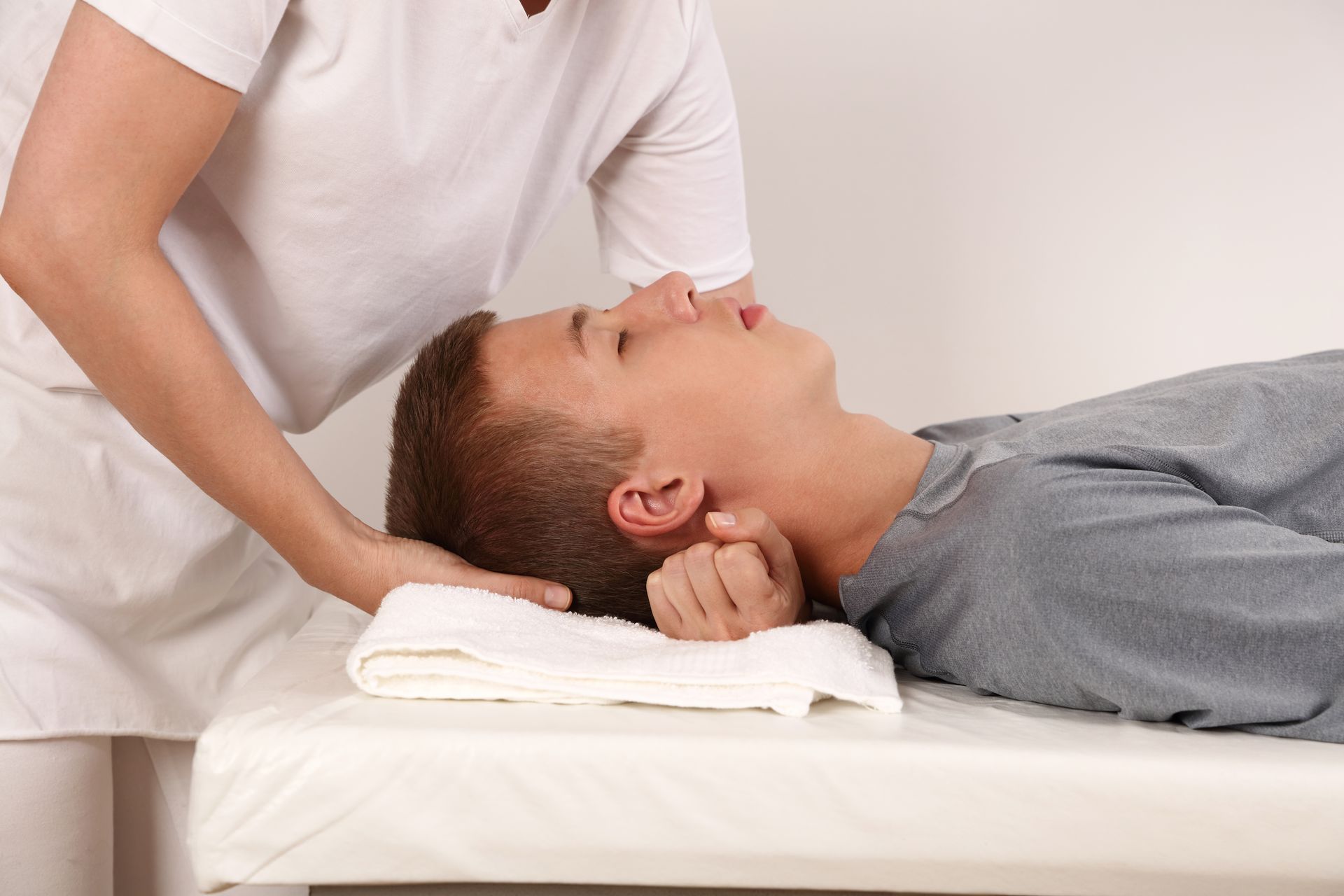 A man is laying on a bed getting a massage from a nurse.