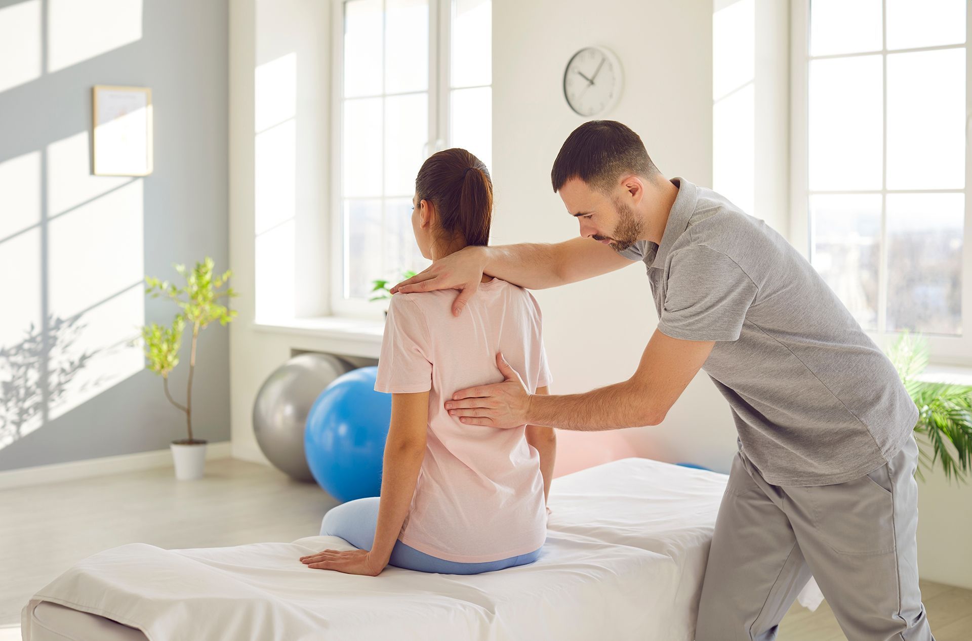 A man is helping a woman stretch her back on a bed.