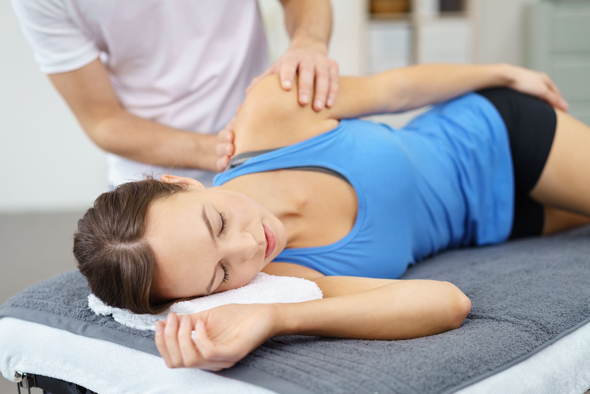 A woman is laying on a table getting a massage from a man.