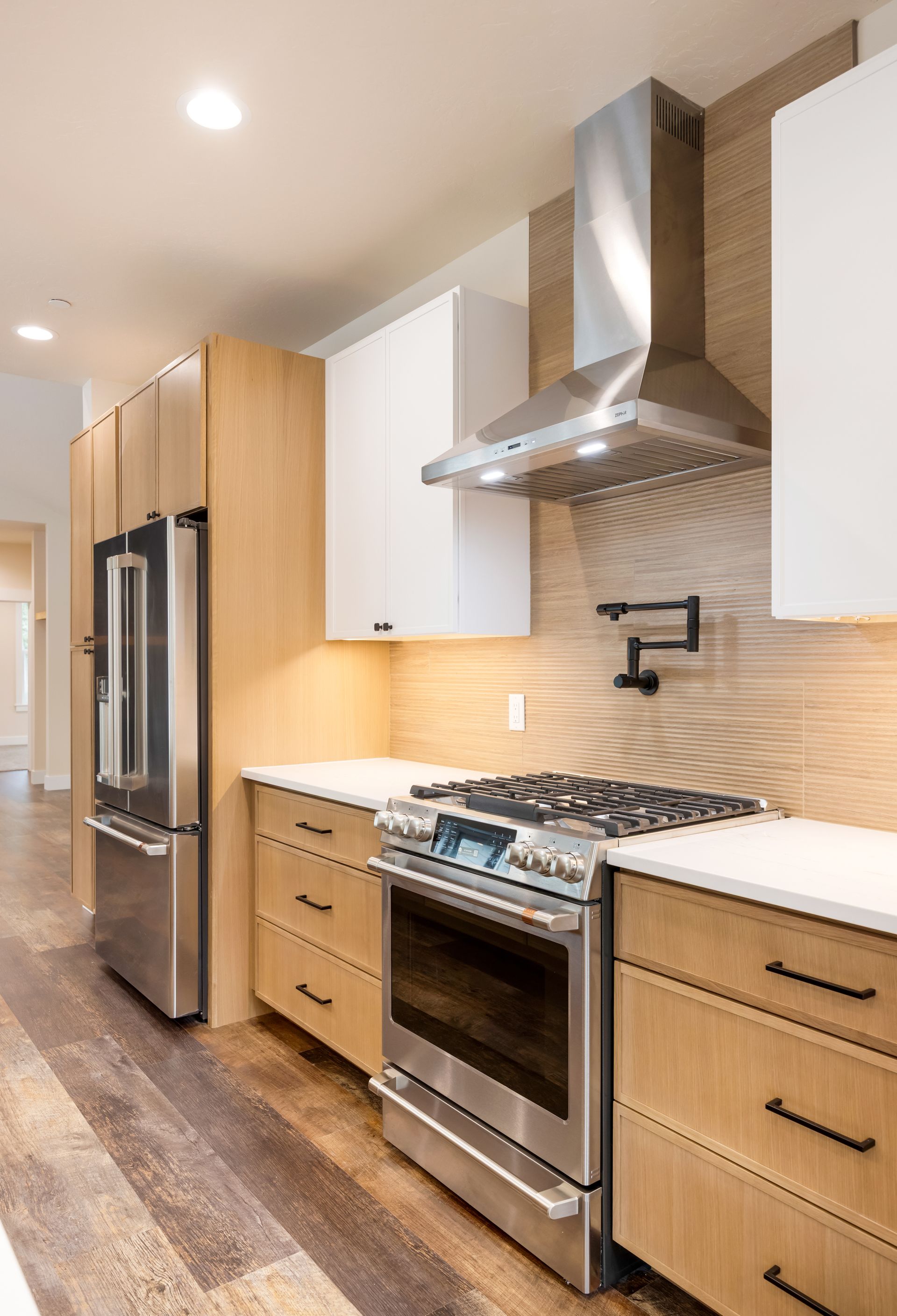 Modern kitchen with stainless steel appliances, white cabinets, wood accents, and a tiled backsplash