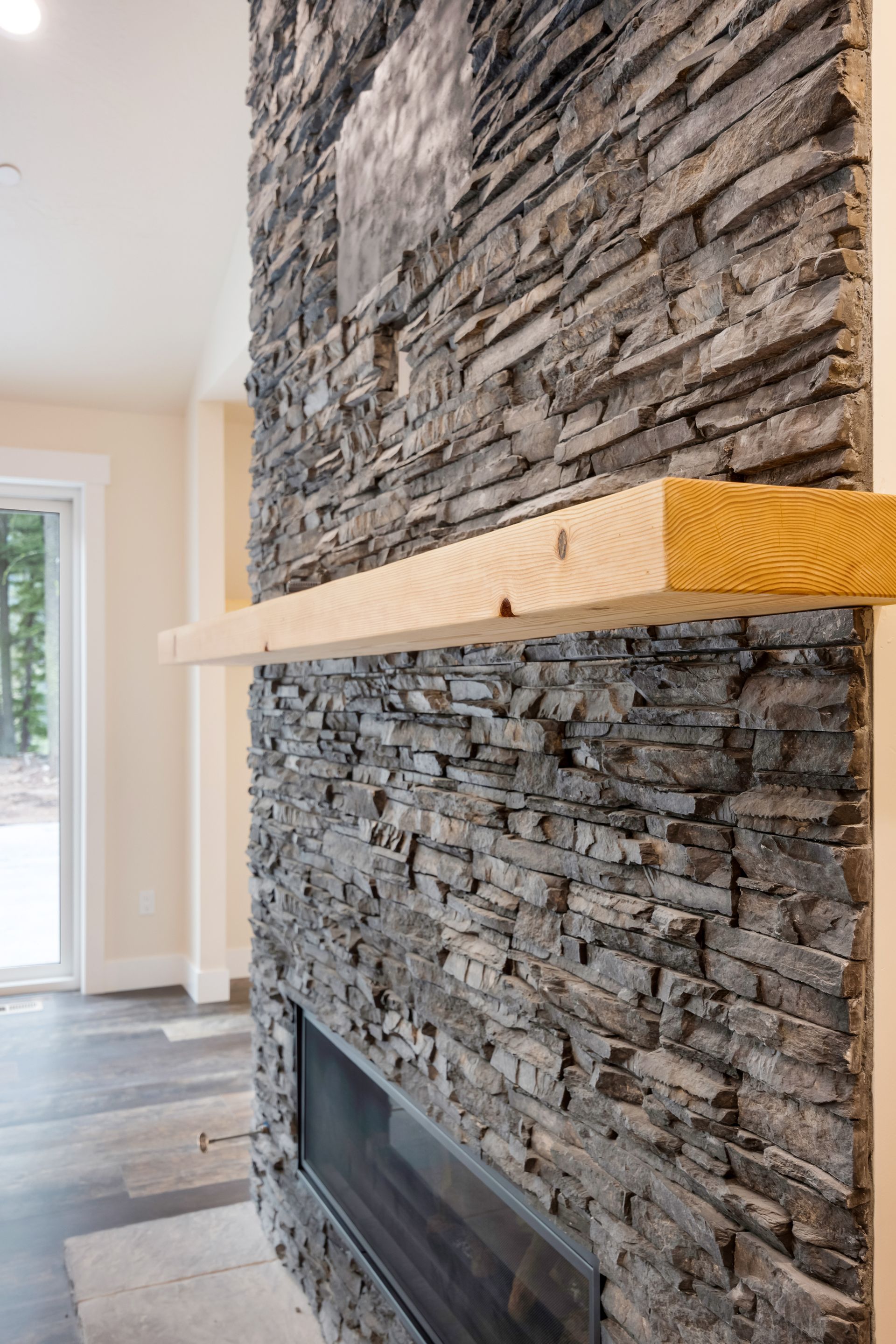 Stone fireplace with a wooden mantel in a bright room