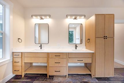 Modern bathroom vanity with double sinks, mirrors, wall lights, and a tall wooden storage cabinet