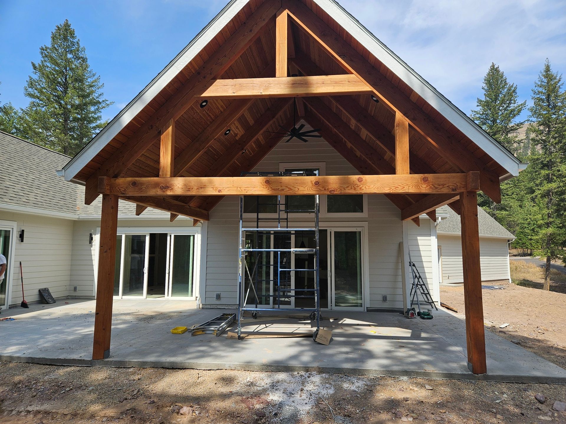 Front view of a house under construction with a wooden porch roof and exposed framing
