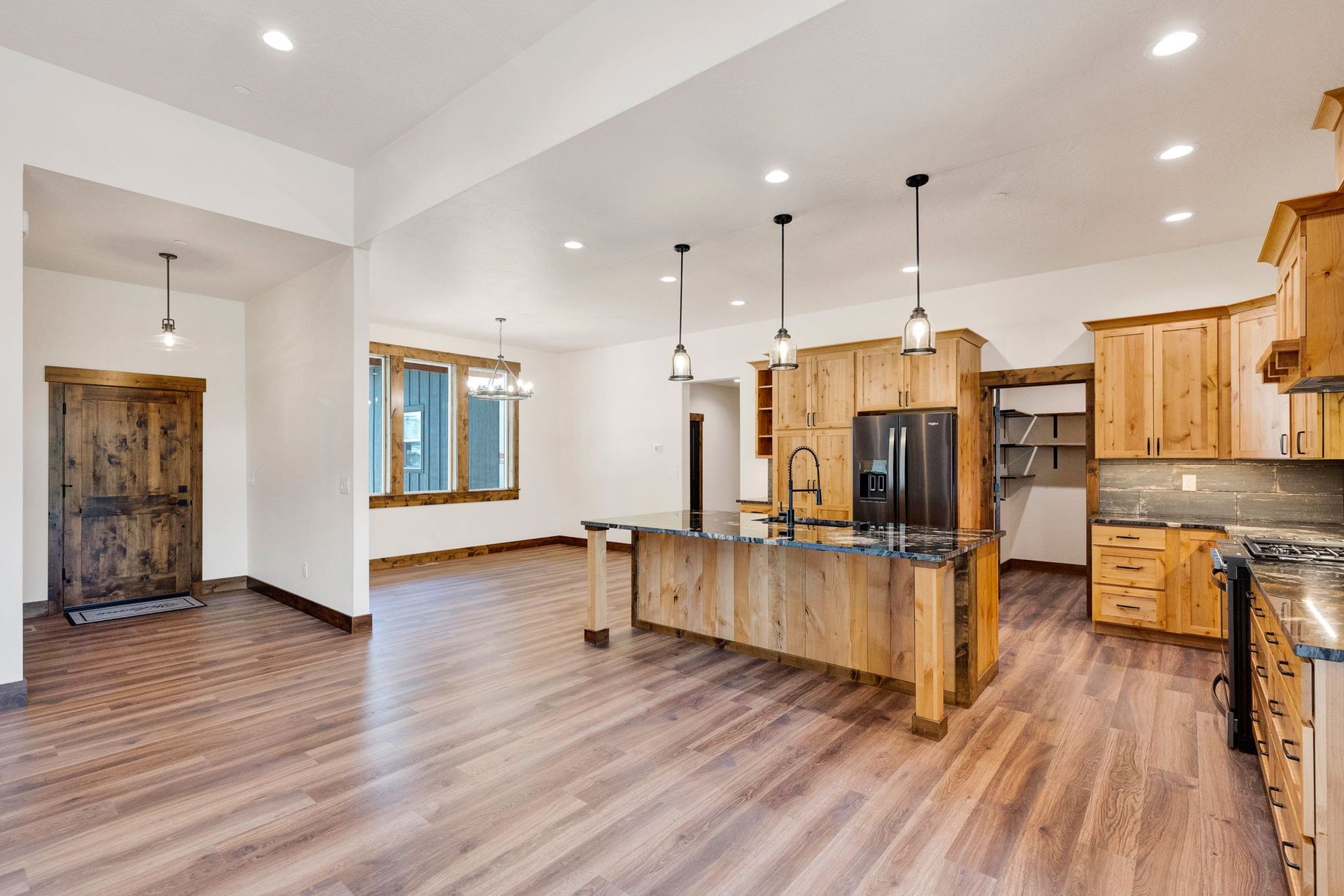 Bright open kitchen with wood cabinets, island, pendant lights, and hardwood floors