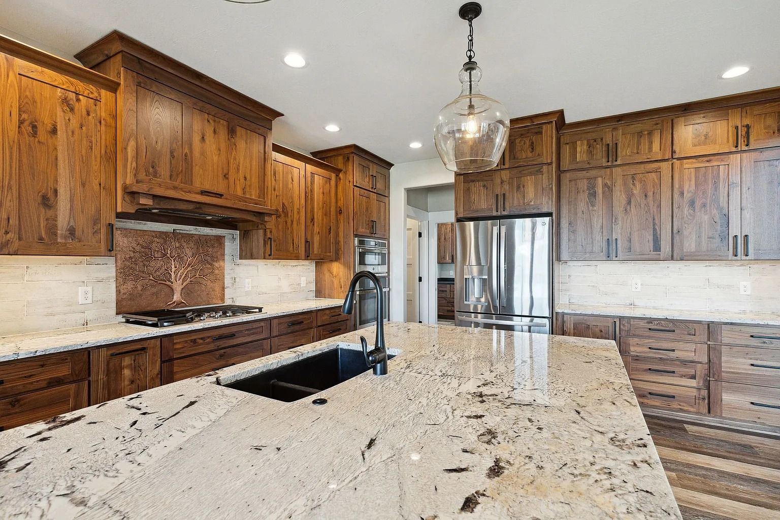 Modern kitchen with wood cabinets, granite island, stainless steel appliances, and pendant lighting
