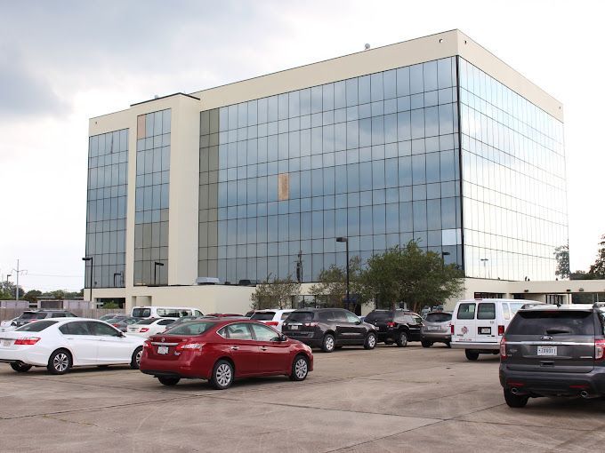 A lot of cars are parked in front of a large building
