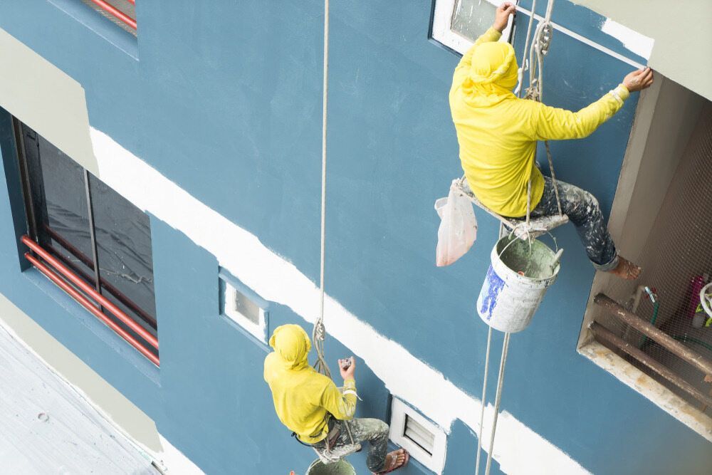 Two Men Are Painting the Side of a Building — Prota NT in Howard Springs, NT